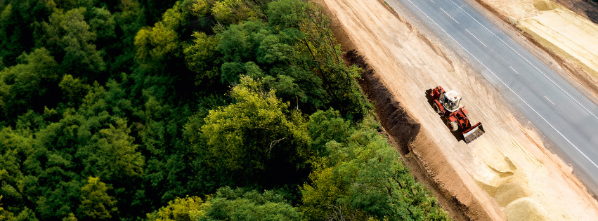 Aerial view of roadworks cutting through green forest, protected by Shell PANOLIN biodegradable lubricants